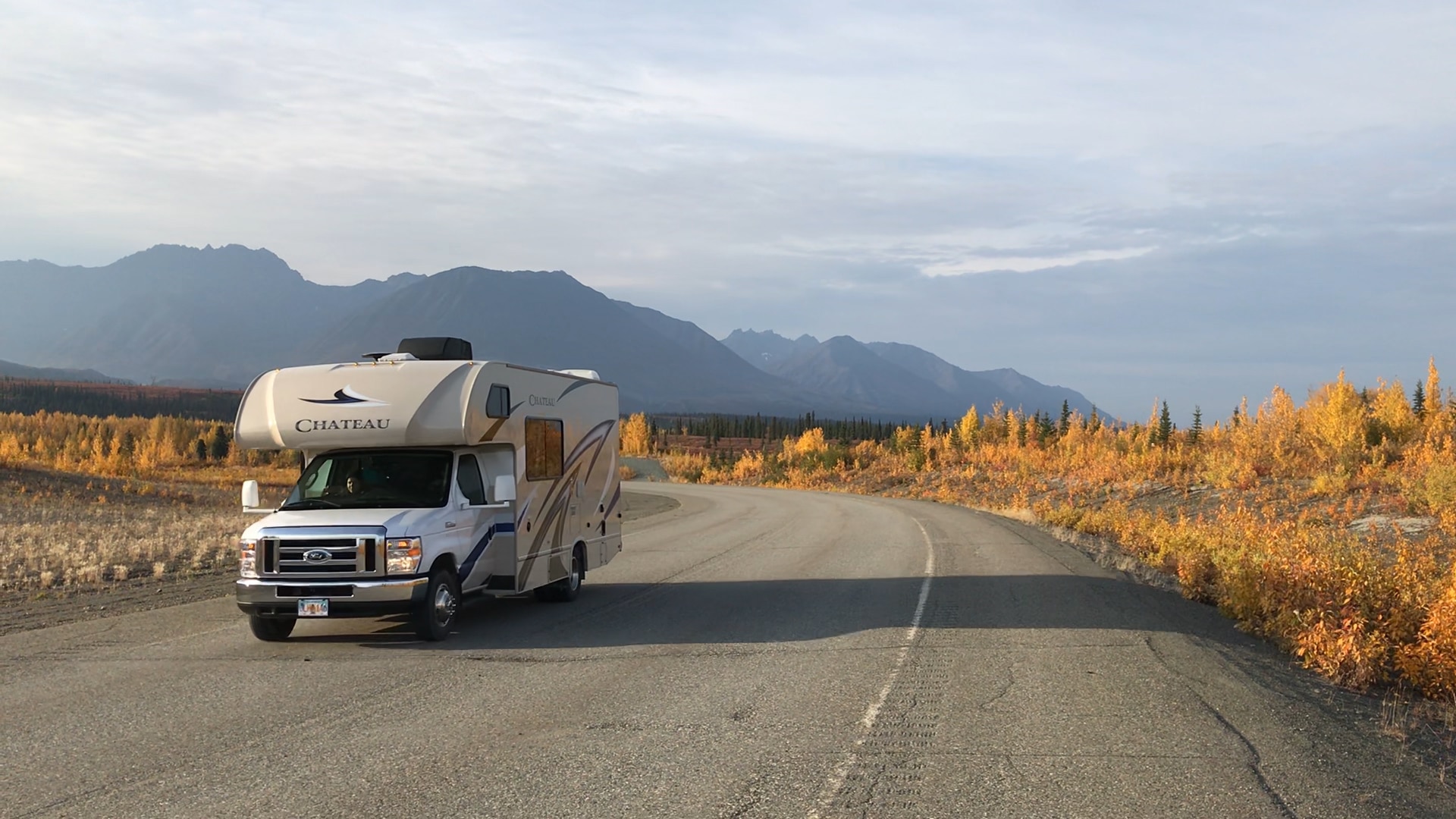 A 19-24ft Motorhome driving on a road during autumn sunset with mountain range in the background