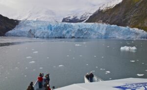 people on a boat taking pictures of a big glacier