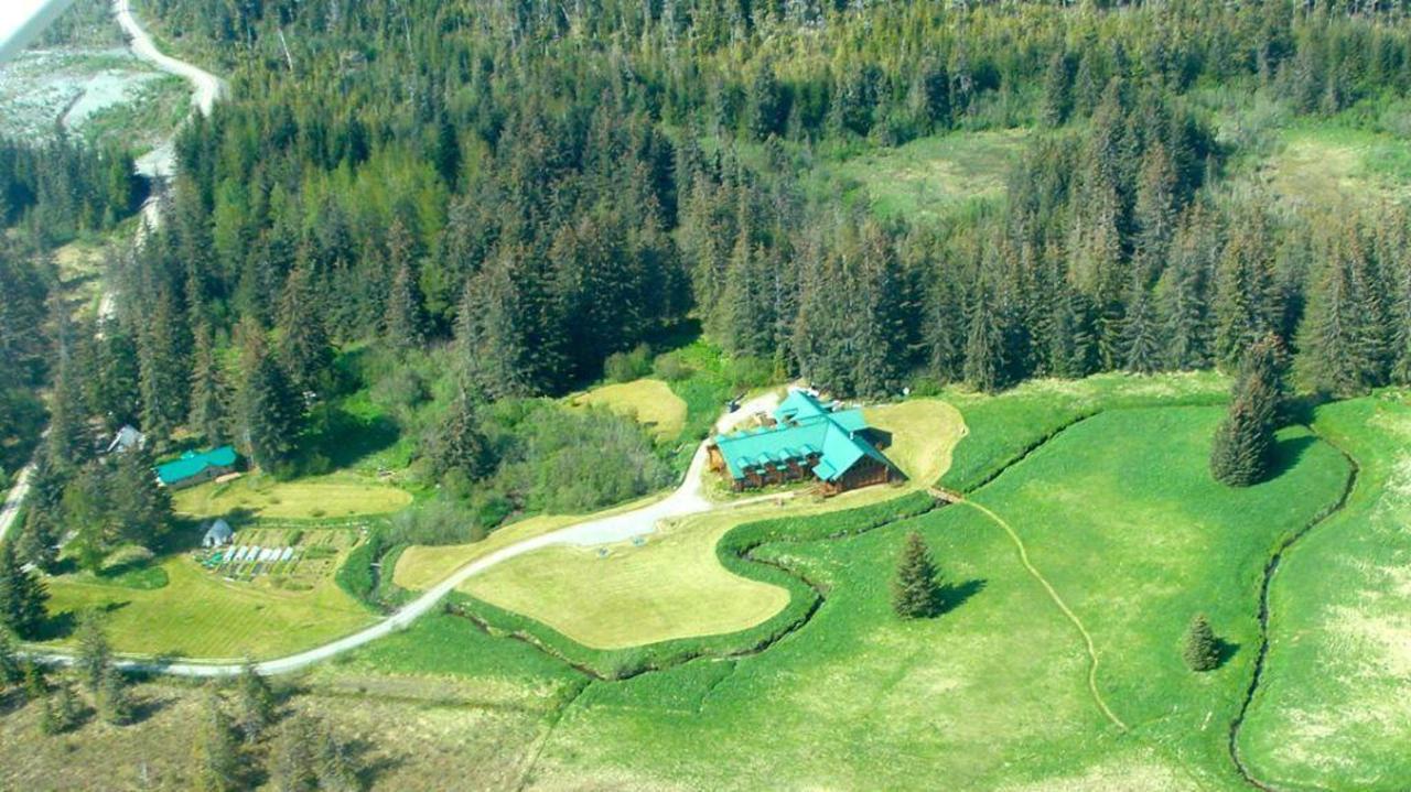 Aerial view of a lodge surrounded by green fields and woods