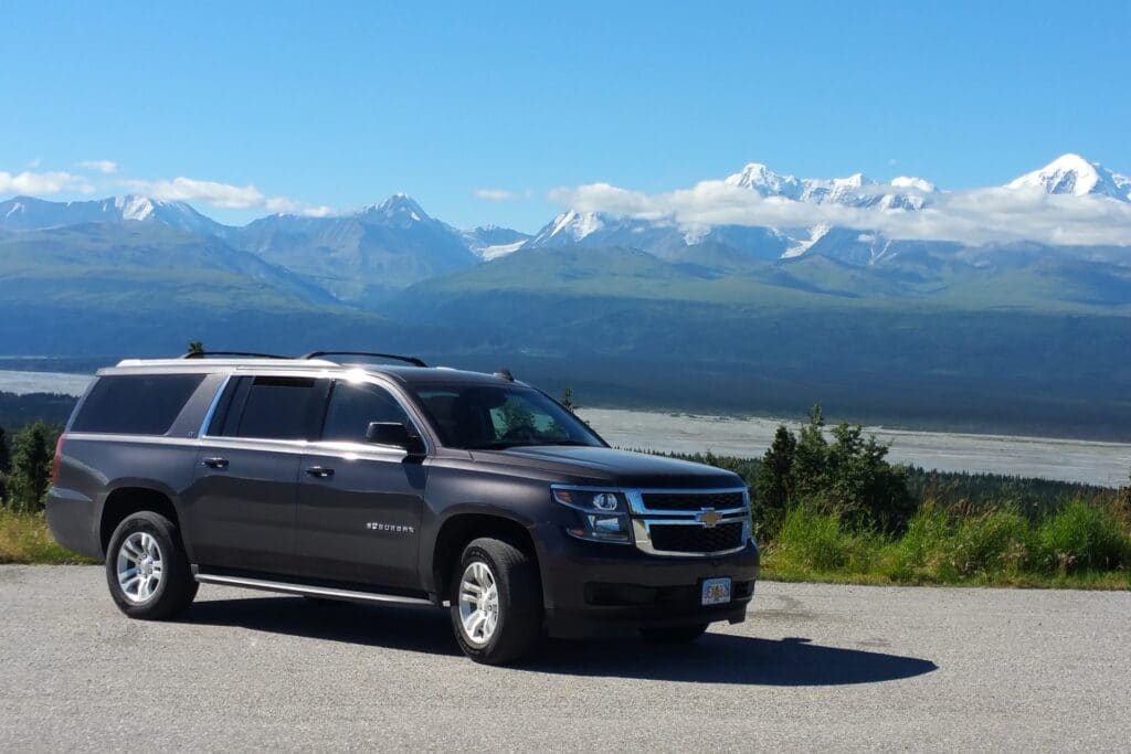 an SUV during daylight on a gravel lot with a mountain range in the background