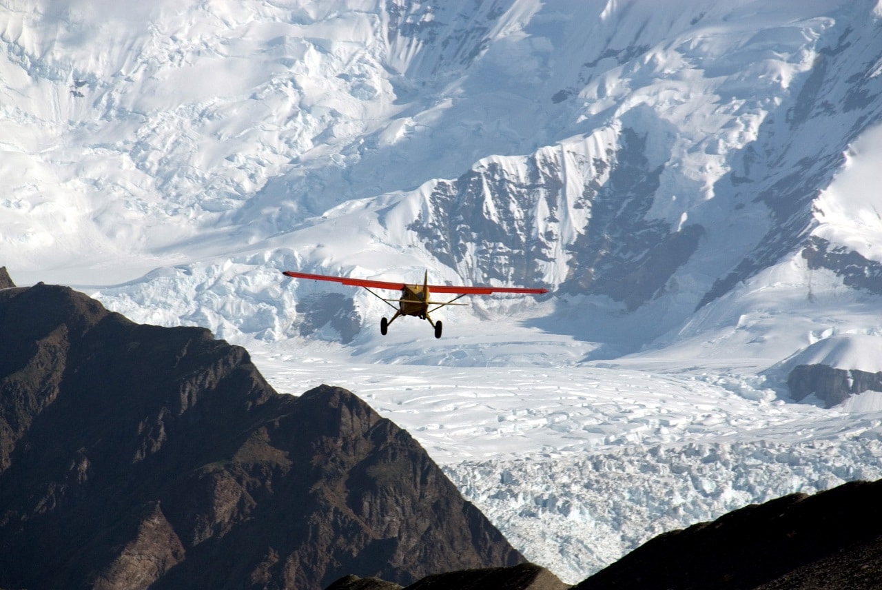 small red plane in front of a glacier