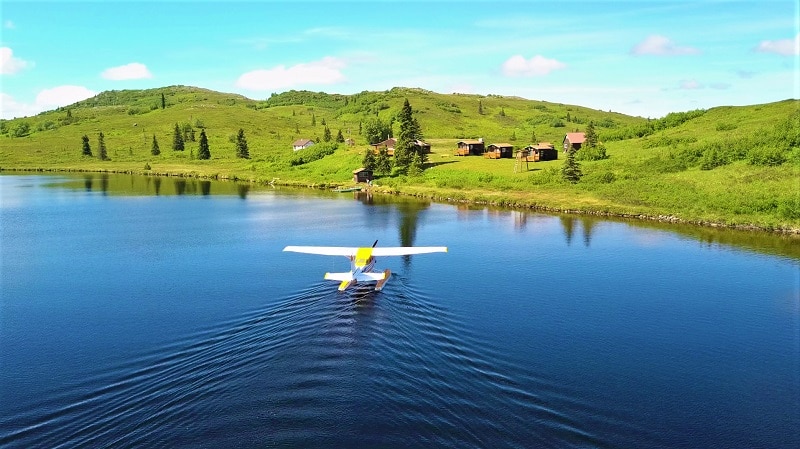 a floatplane landing on a lake in front og Caribou Lodge Alaska