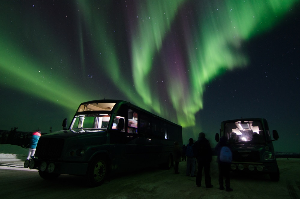 Dancing green Aurora over 2 busses and some people