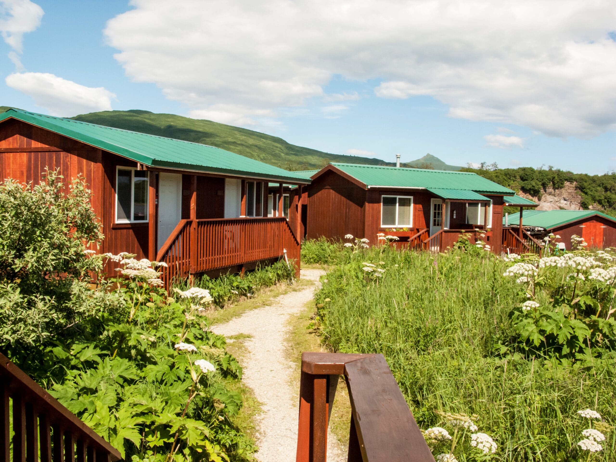 a path along some cabins red with green roof