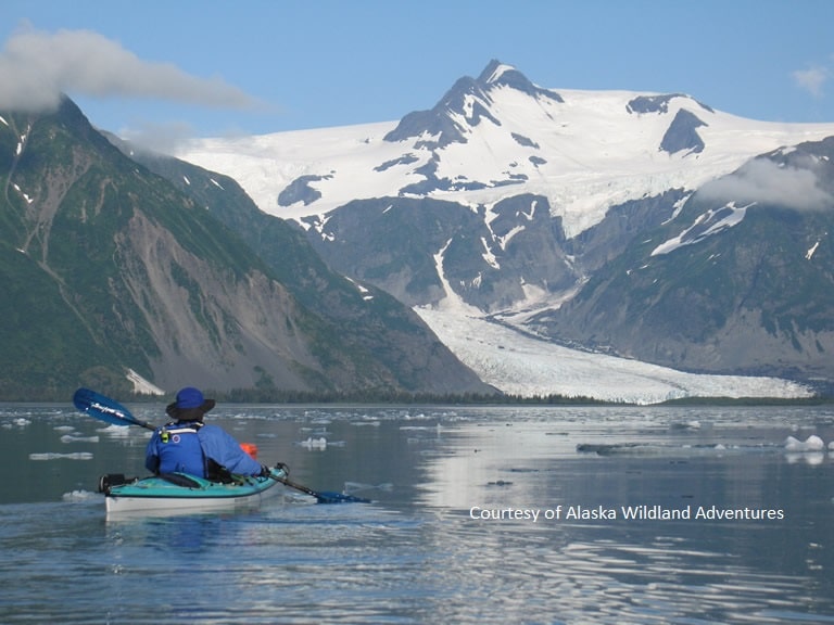 a kayaker paddling on the sea towards a glacier