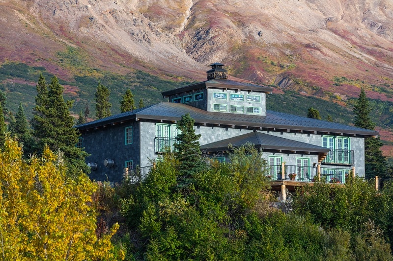 a ncie lodge surrounded by trees in fall colors mountains in the back