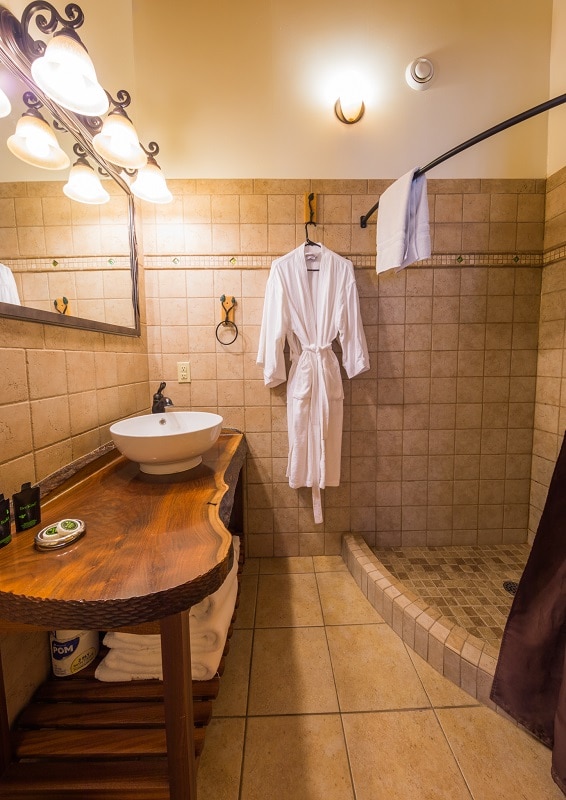 a bathroom with a wooden table, a white bathrobe hanging at the wall