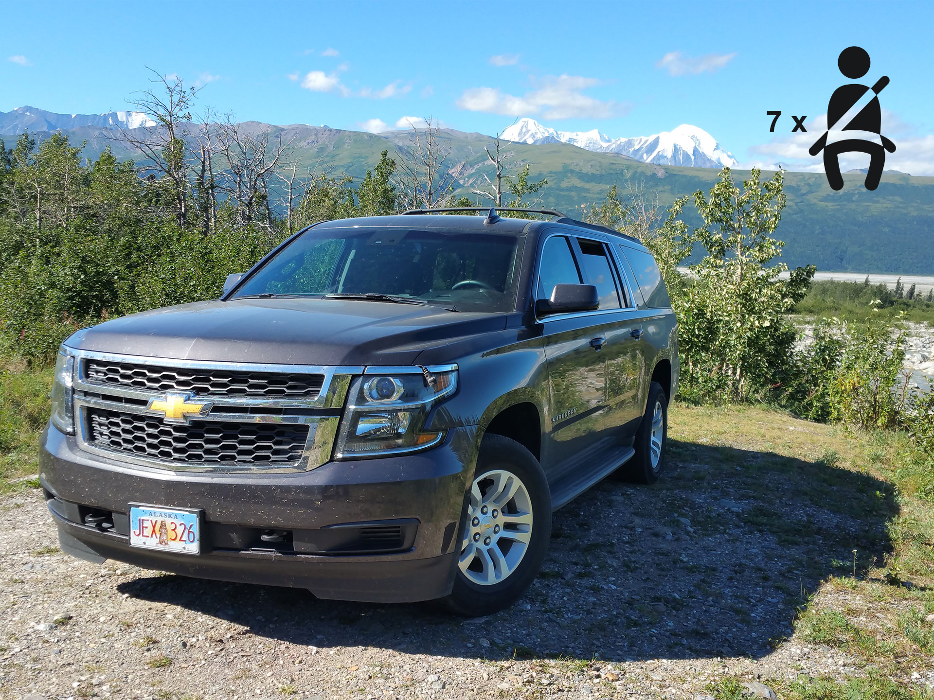 a black suv on a gravel lot with some bushes and a mountain range in the background and an icon in the top right corner which indicates that there are seven seat belts available