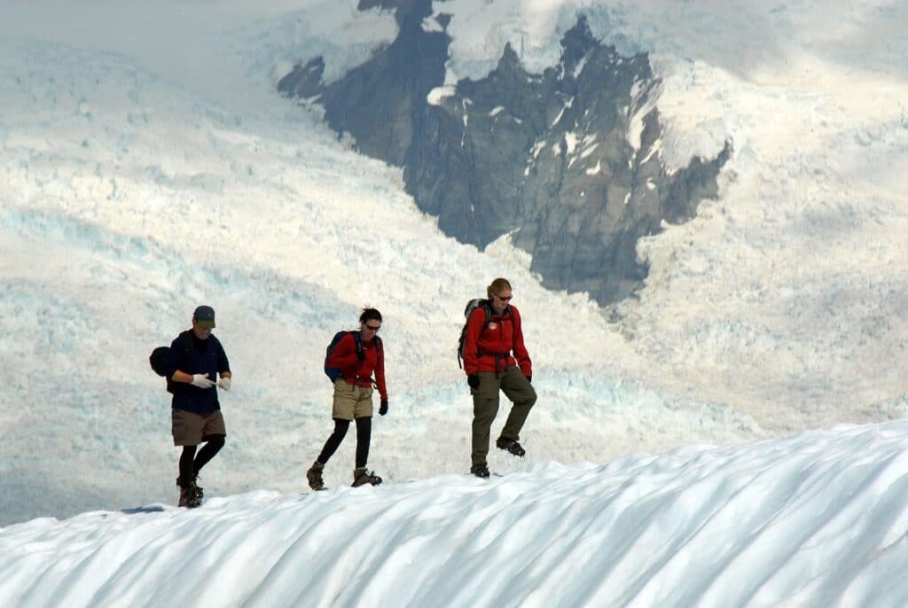 three people hiking on a glacier ridge
