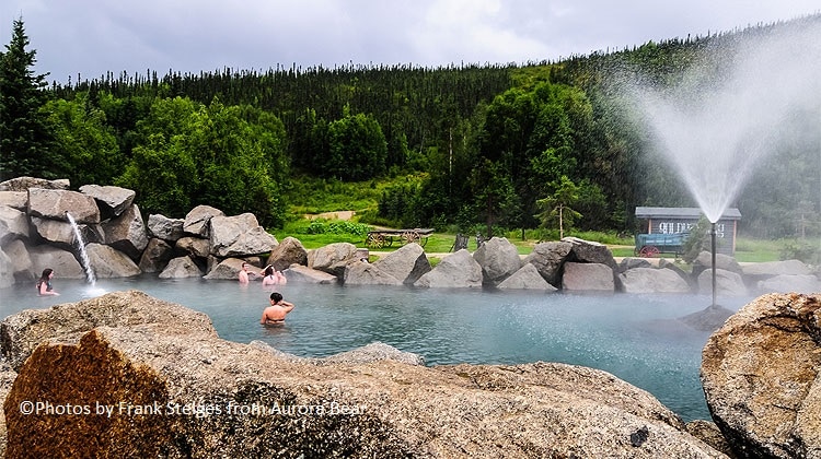 People taking a bath in natural springs surrounded by rocks during daylight