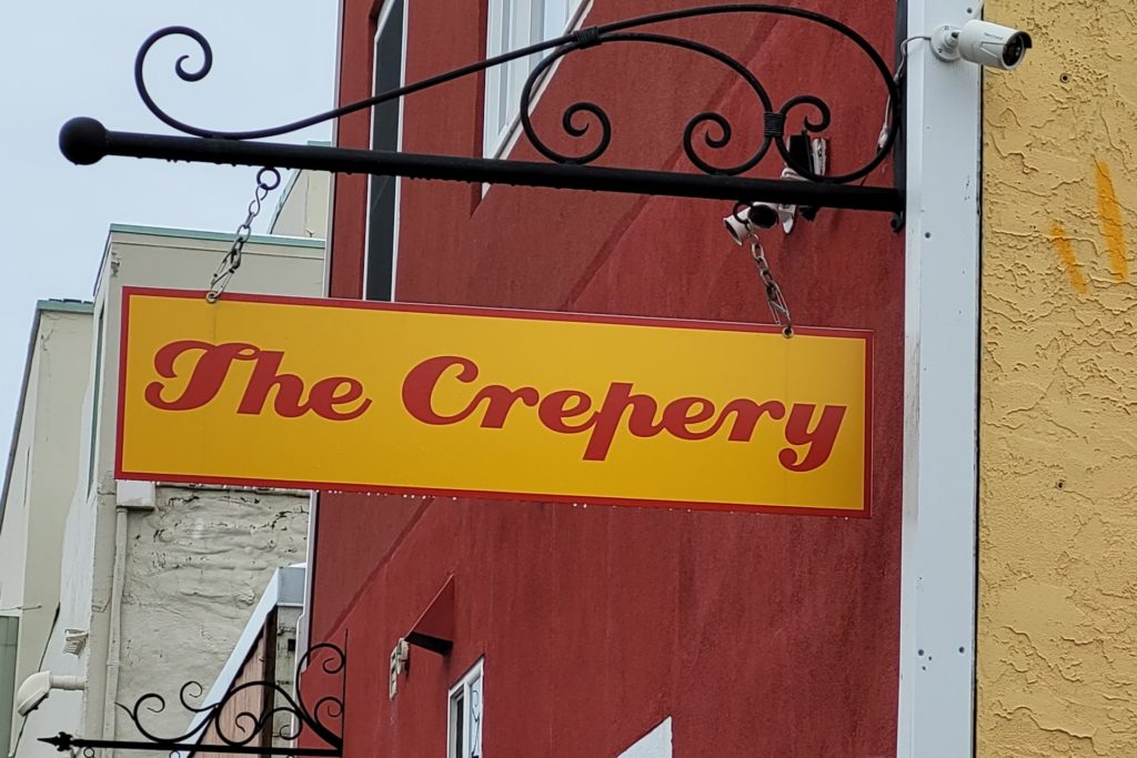 A sign of a restaurant called "the crepery" during daylight