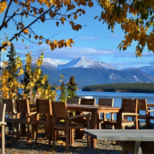 a beergarden at a lake with mountains in the back fall colors
