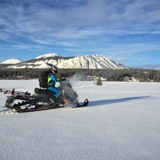 a snowmobile rider in front of a mountain